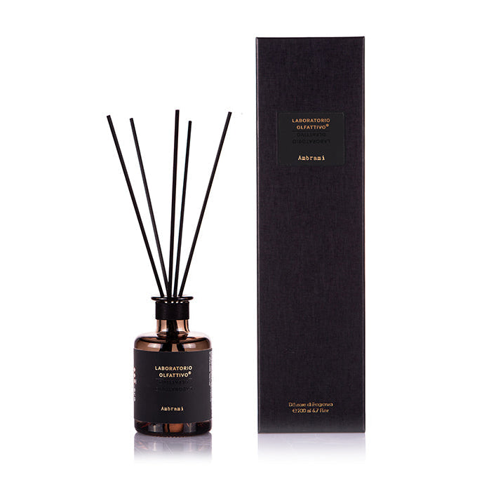 A dark fragrance diffuser bottle, accompanied by a black box with gold text, presumably the product's packaging.