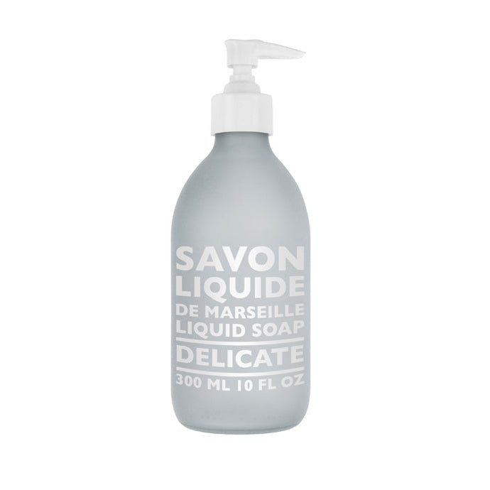 A frosted glass bottle with a pump dispenser labeled 'SAVON LIQUIDE DE MARSEILLE DELICATE', containing Delicate Liquid Soap.