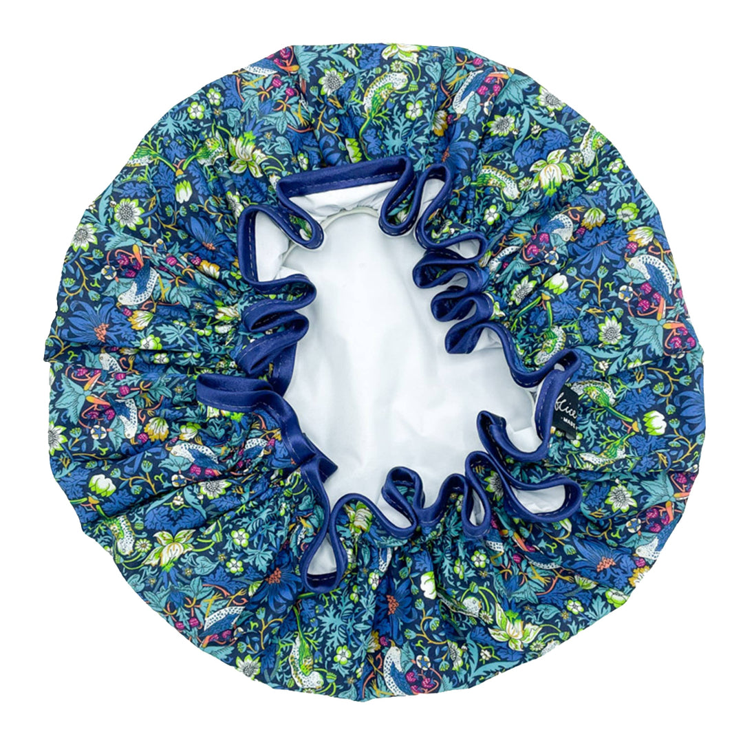 A floral patterned shower cap with blue satin ribbon edging.