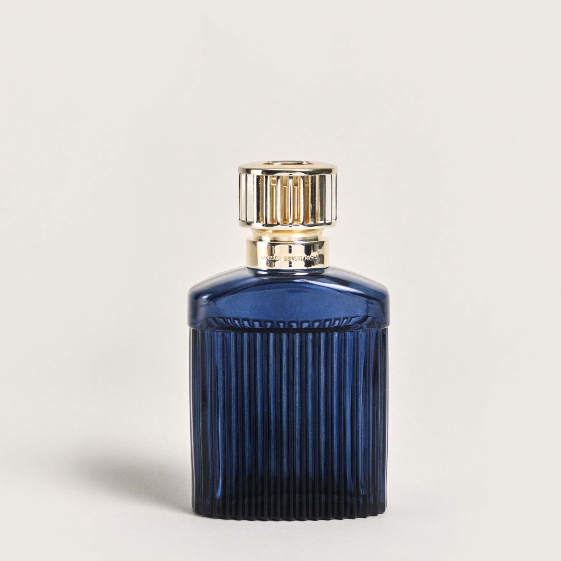 Blue perfume bottle with a gold cap on a light gray background