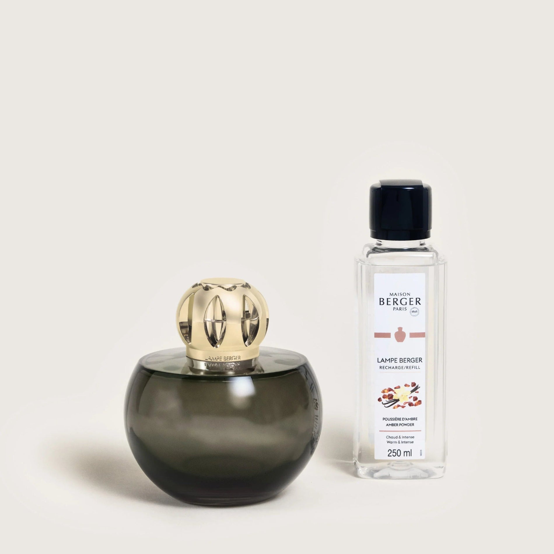 A Maison Berger Paris lamp with a grey shade and a gold-colored top, accompanied by a bottle of fragrance fuel.