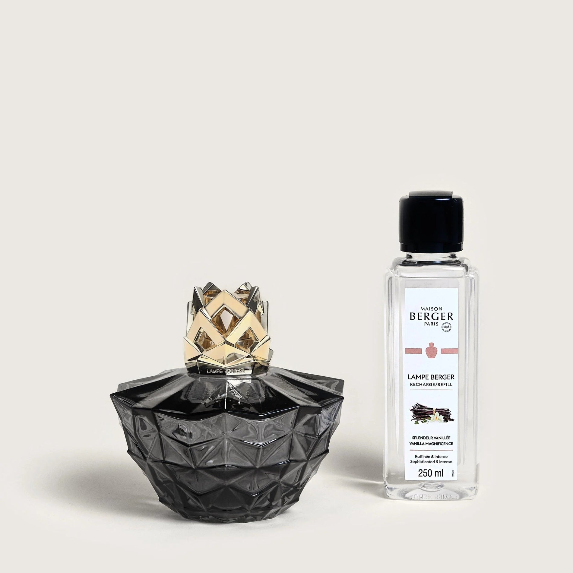 A black geometric fragrance lamp with a golden cap alongside a bottle of Maison Berger catalytic refill fragrance fuel.