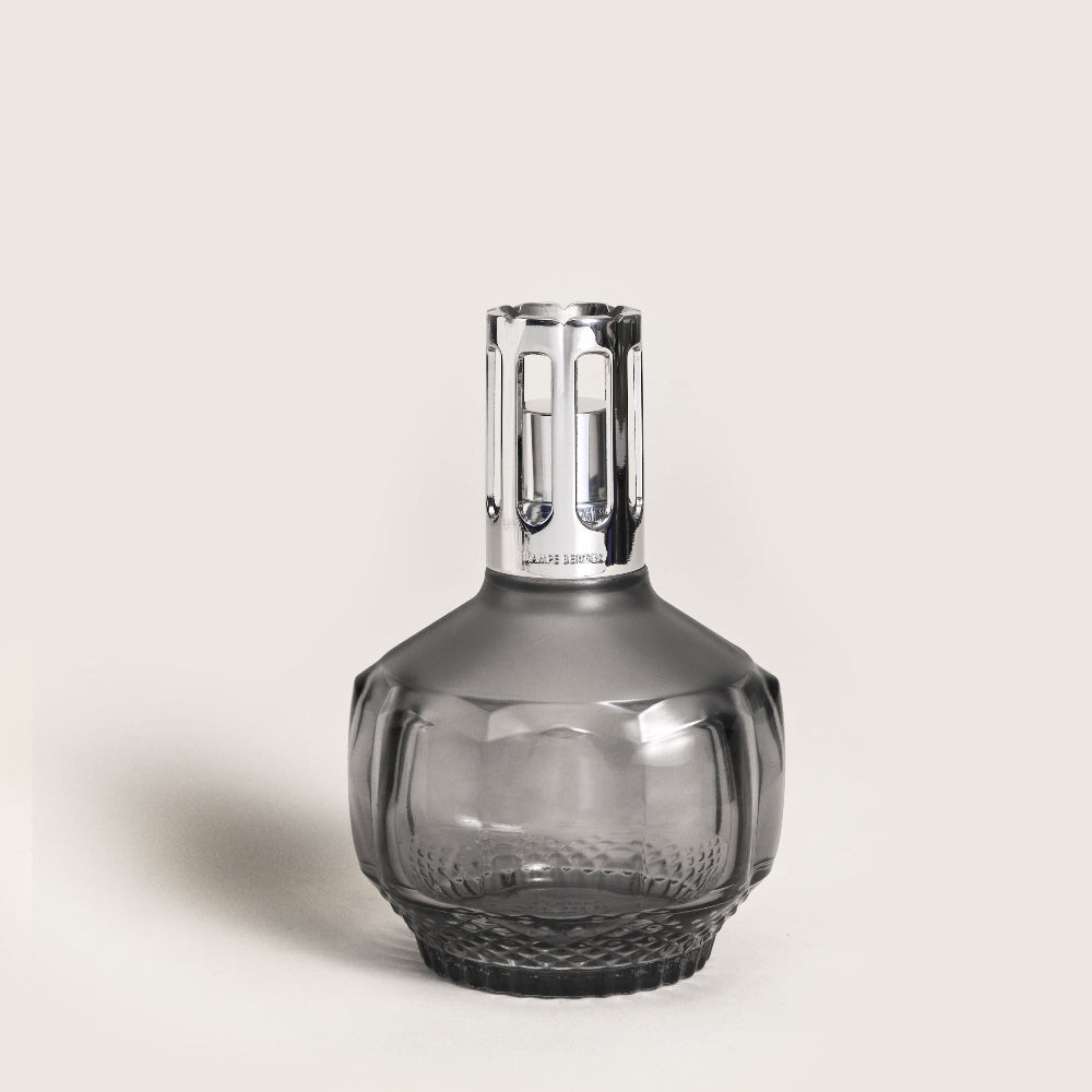 Gray glass carafe with silver cap on a light beige background