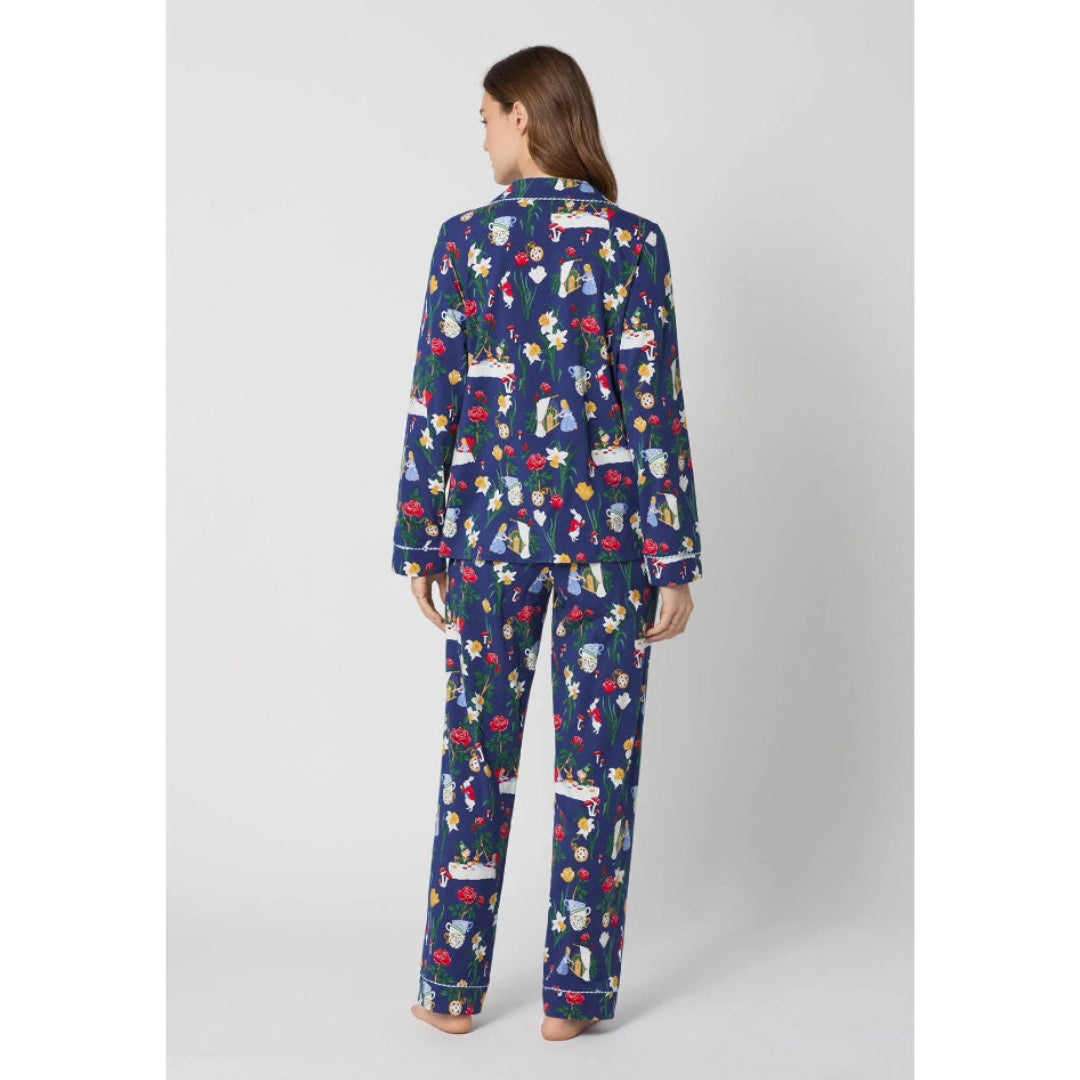 Woman wearing a blue pajama set with Alice in Wonderland print on a white background