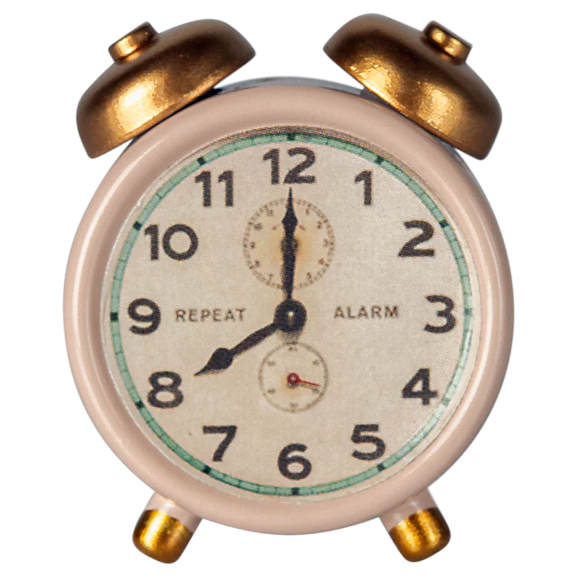 A small, traditional style alarm clock with a white face, black numbers, and gold-colored metal body.
