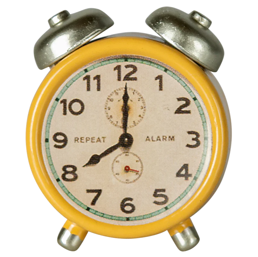A small yellow and silver metal alarm clock with a white clock face and black numerals.