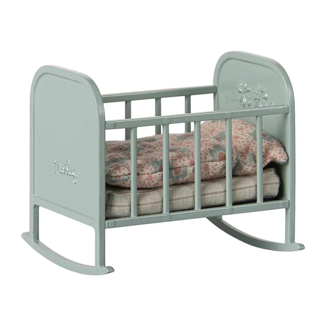 Blue baby crib with floral bedding on a white background