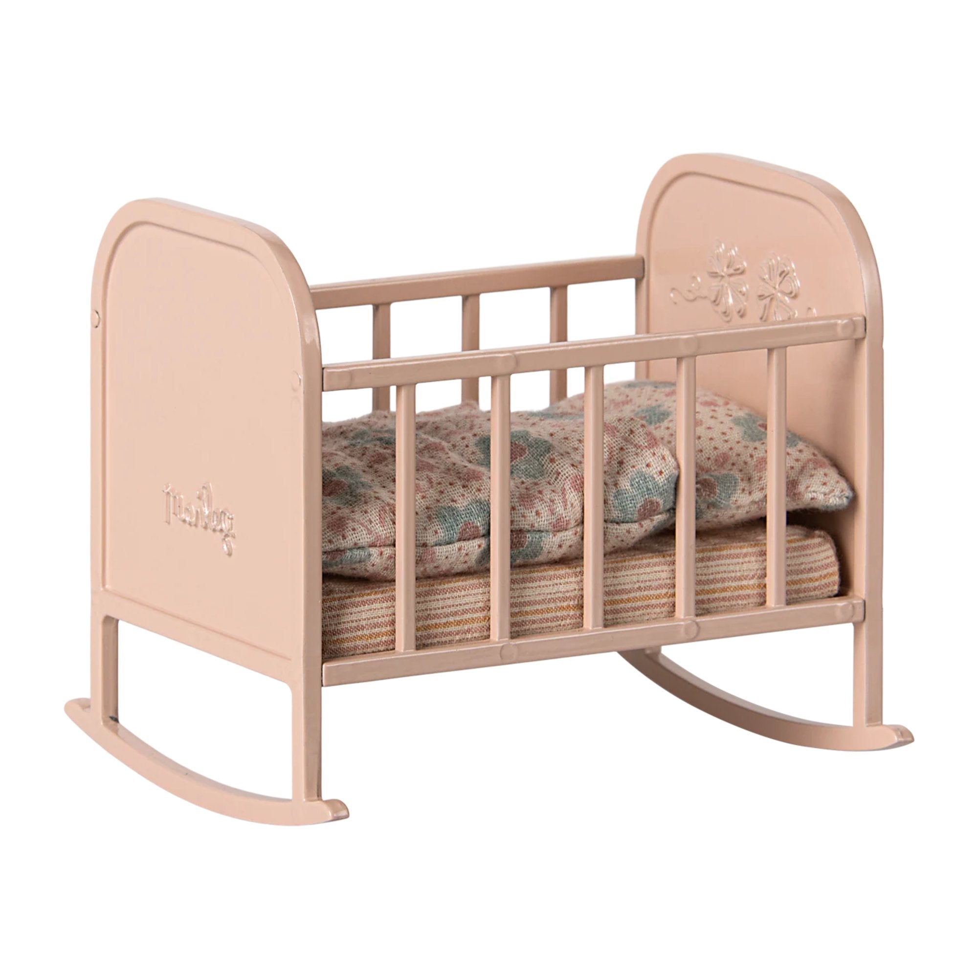 Pink baby crib with floral bedding on a white background