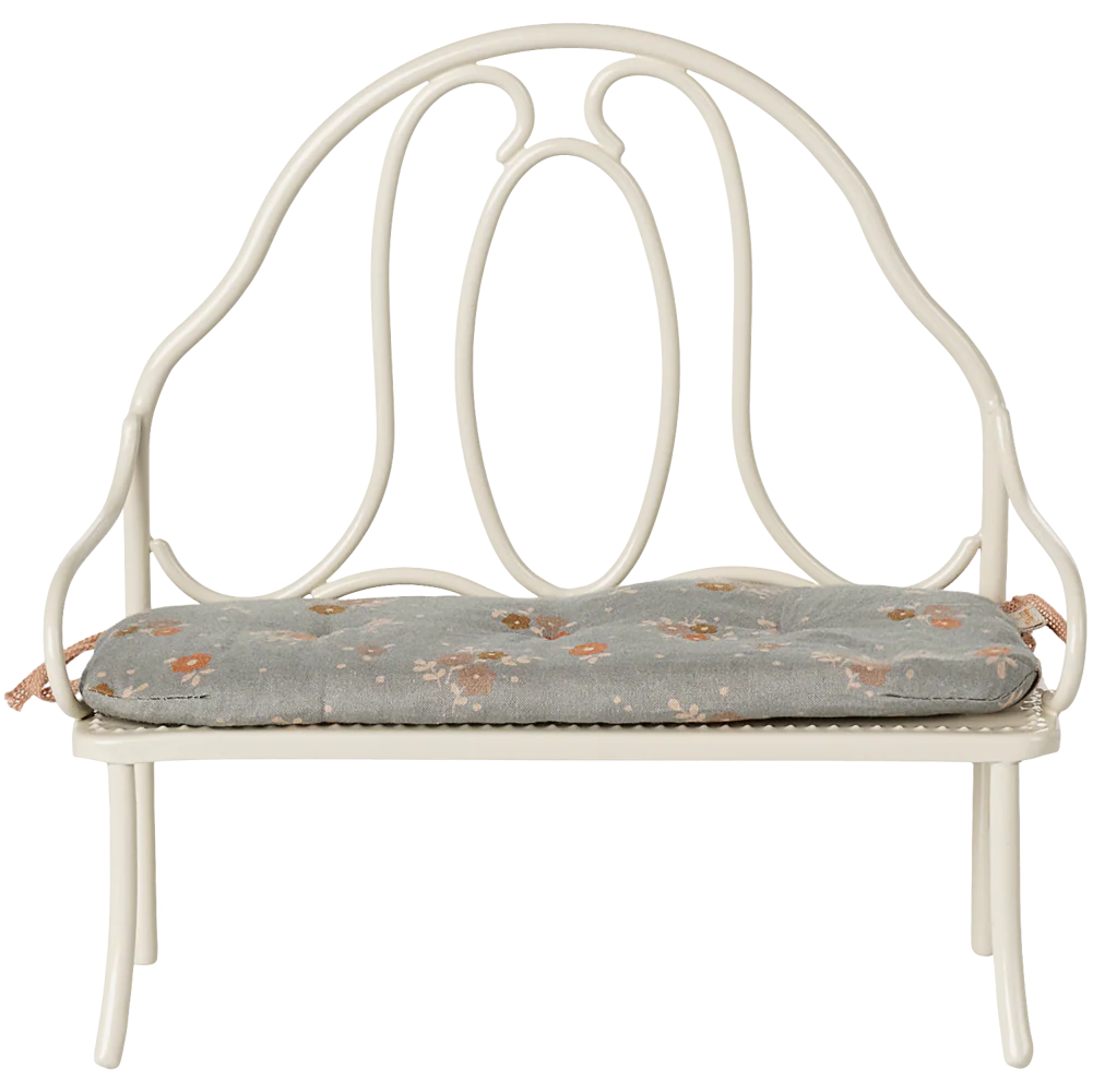 White metal bench with floral cushion on a white background