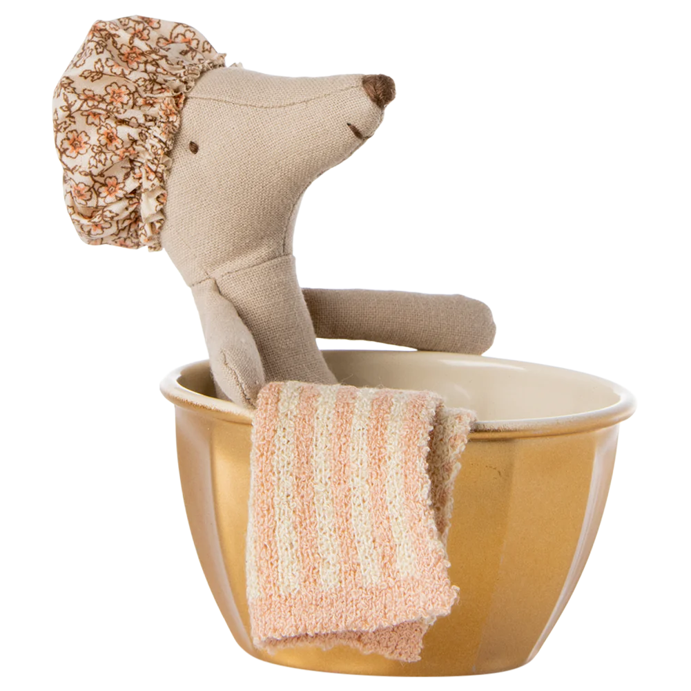 A toy mouse with a shower cap standing in a golden metal bathtub with a towel hanging on the side.