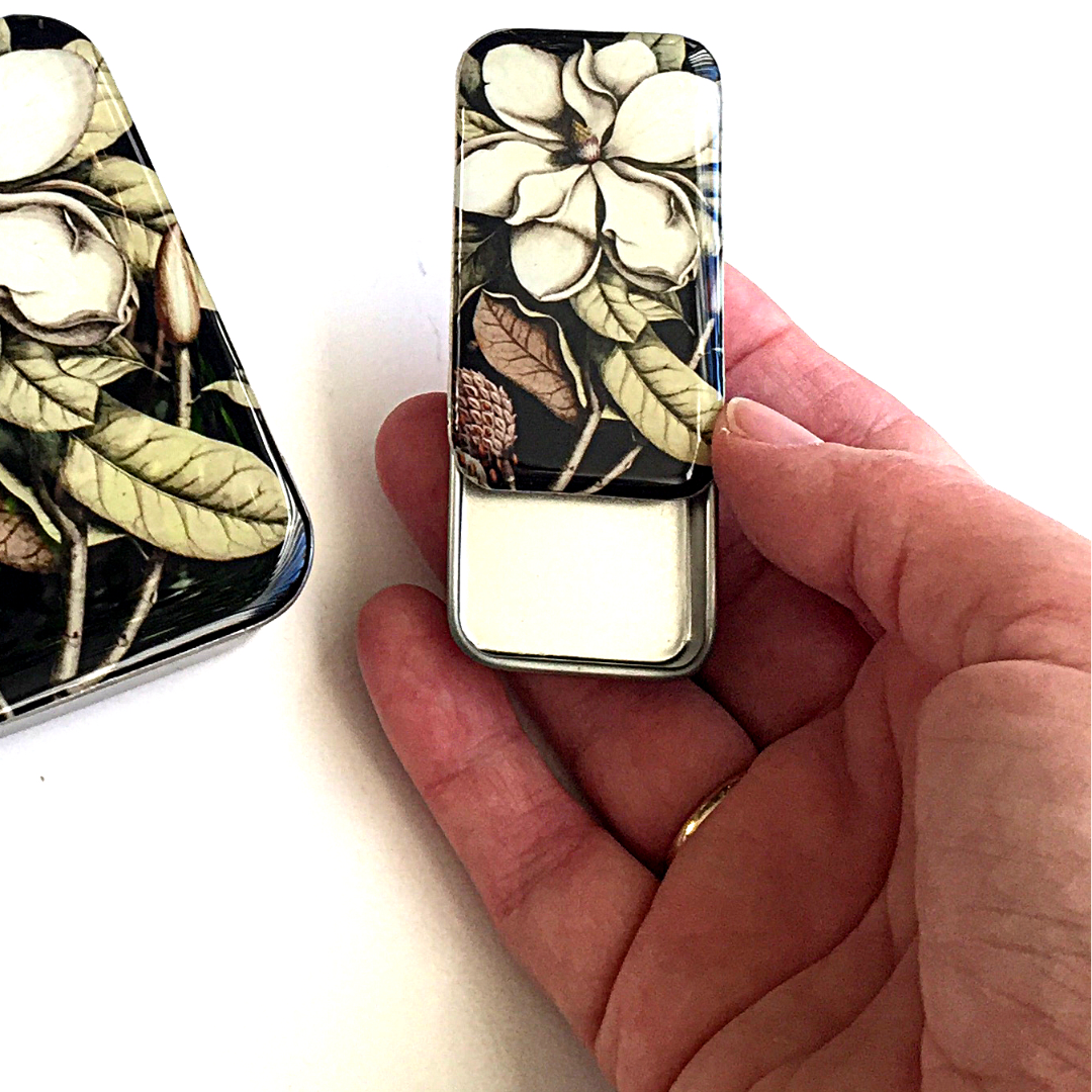 Floral-patterned tin box held by a hand.