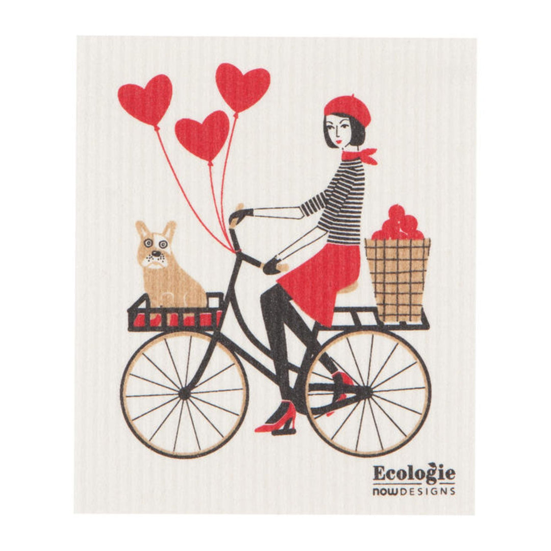 Dishcloth with a design of a woman riding a bicycle with a dog and heart balloons, branded 'Ecologie Now Designs'.