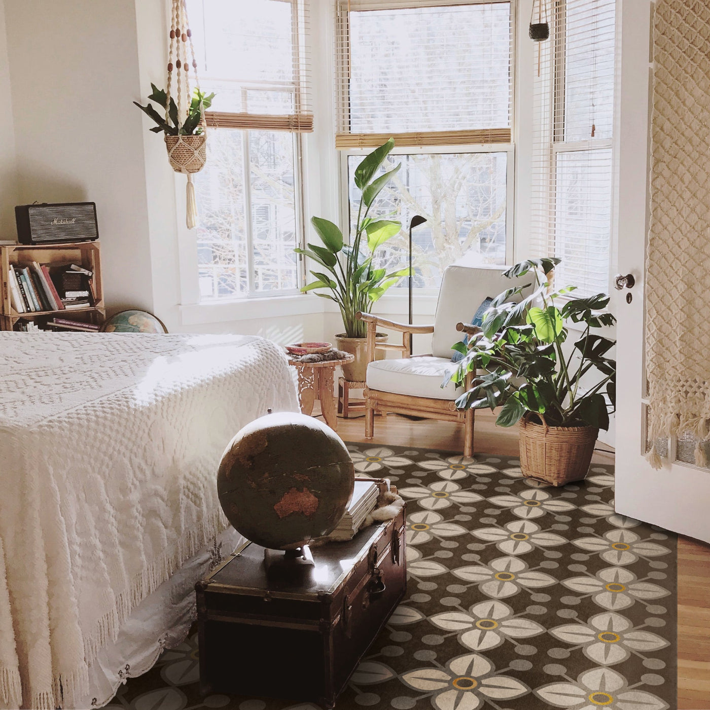 Cozy bedroom with a bed, globe, and plants near large windows.