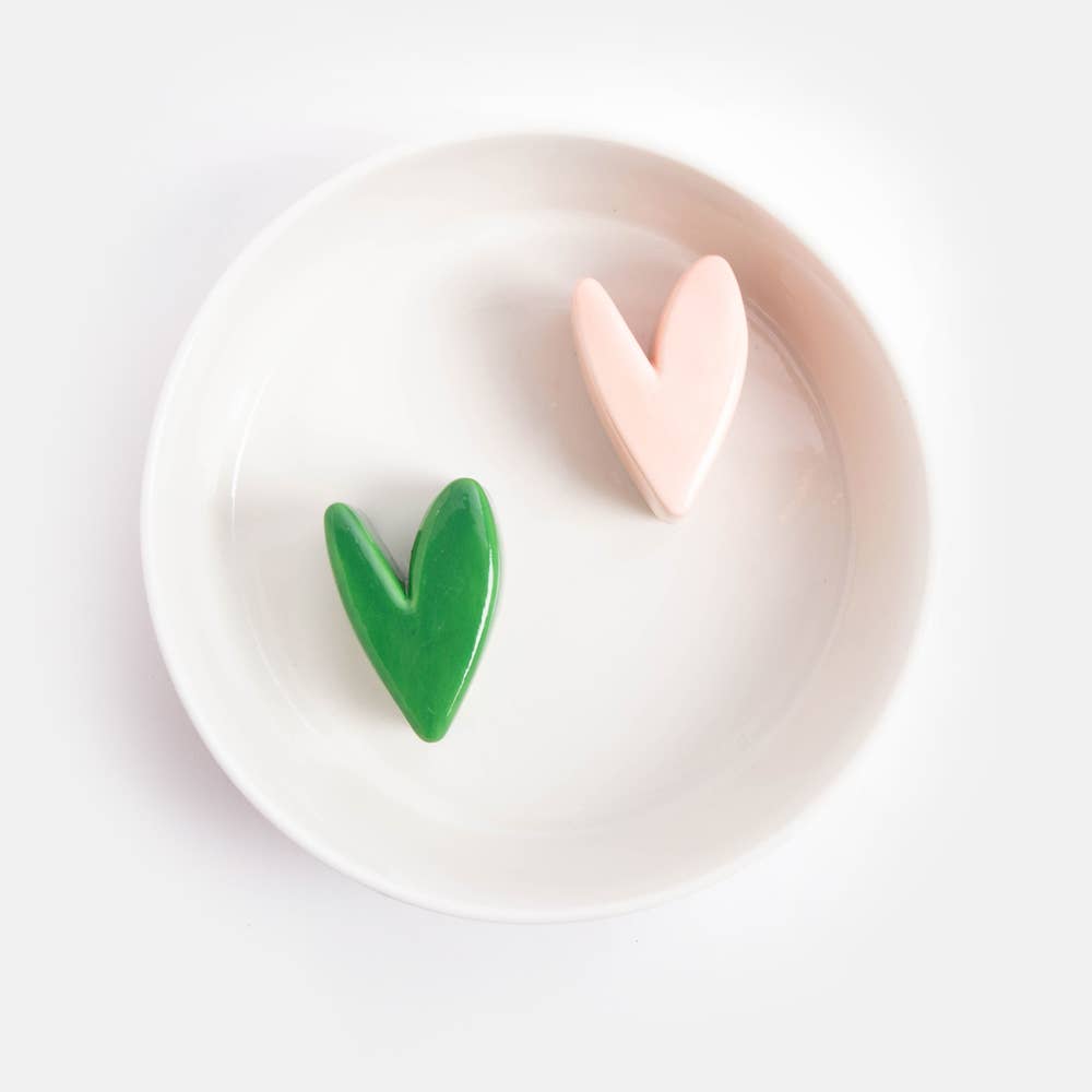 Two heart-shaped objects, one green and one pink, on a white bowl.