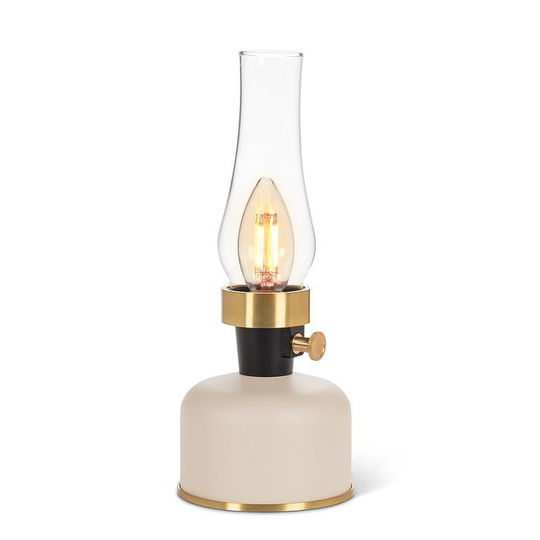 Lamp with a clear glass shade, ivory base, and gold accents on a white background