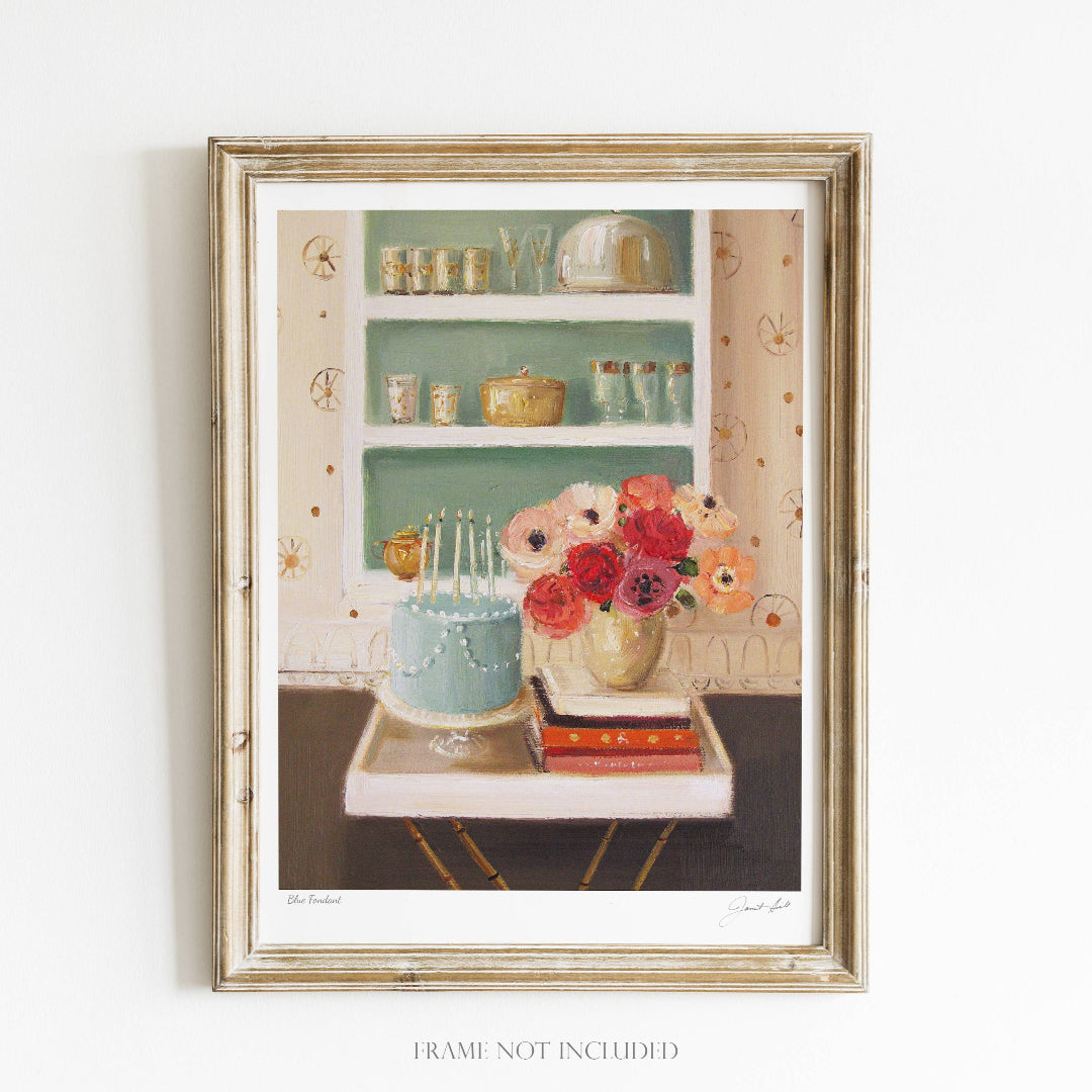 A framed art print featuring a kitchen scene with blue fondant, a vase with flowers, and a shelf with dishes and books. The frame is gold, and the artwork is signed by the artist.