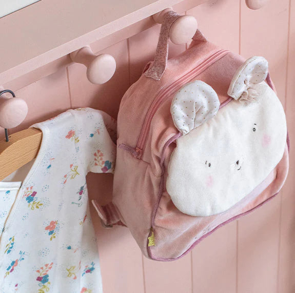 Pink baby outfit with a plush toy on a pink hanger against a pink background