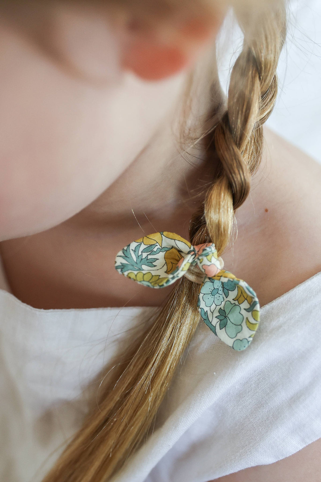 Close-up of a person with braided hair wearing a floral elastic
