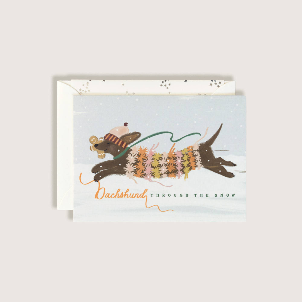 Greeting card with illustration of a dachshund in a sweater and scarf, running through the snow.