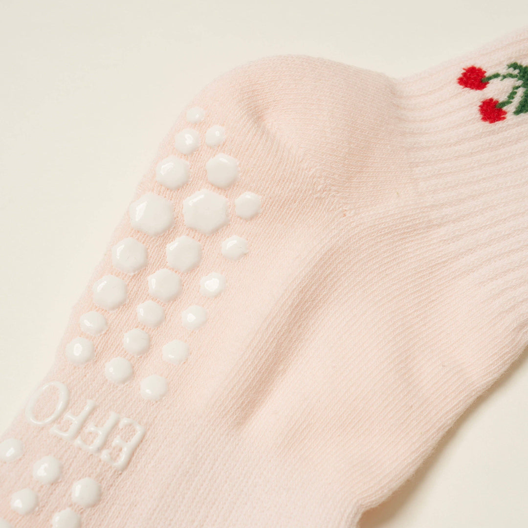 Pink sock with grip dots on a light background