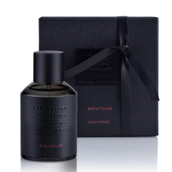 A black bottle of Amberbomb 100ml Eau de Parfum with a label and a black box in the background.