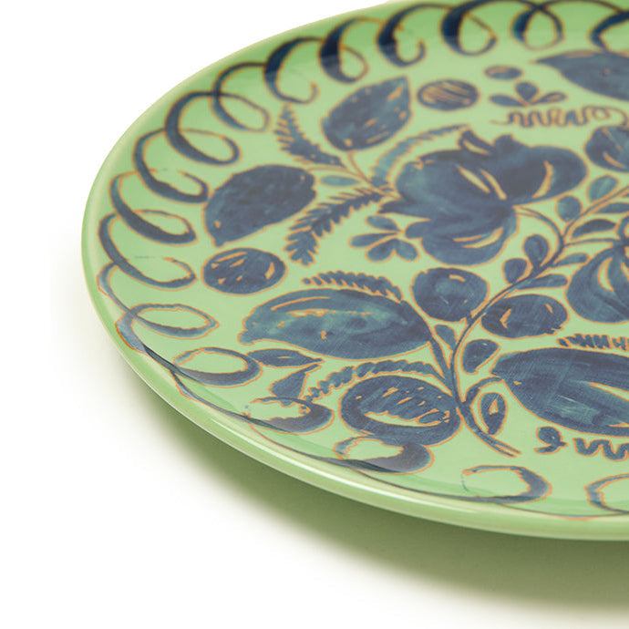 Green ceramic plate with blue floral patterns on a white background