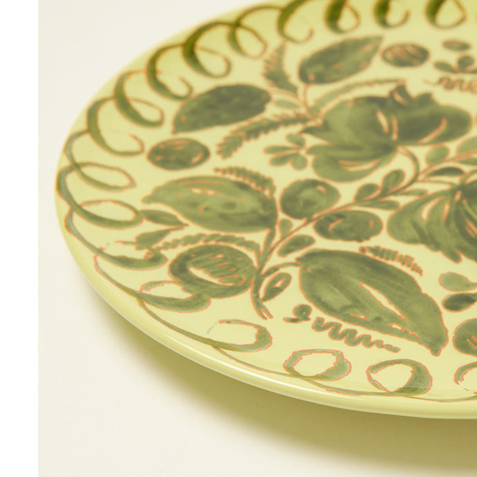 Decorative ceramic plate with green floral pattern on a white background