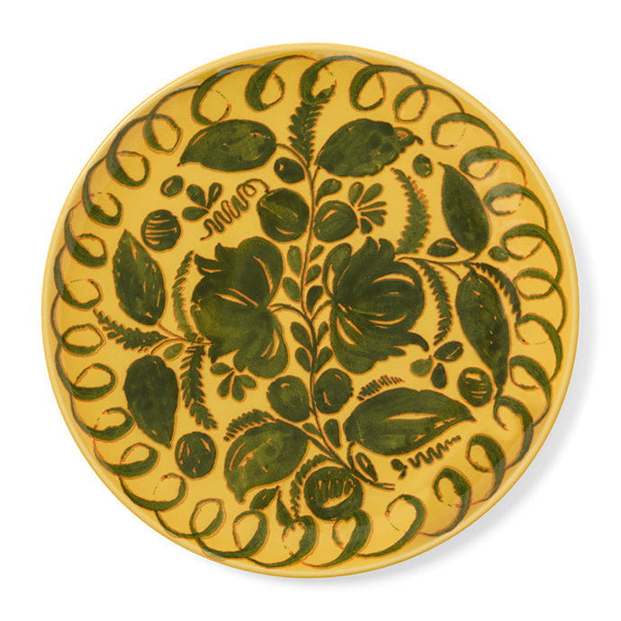 Decorative yellow plate with green floral pattern on a white background