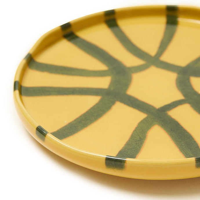 Yellow ceramic plate with green abstract pattern on a white background