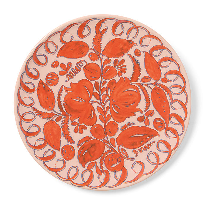 Pink round ceramic plate with floral pattern on a white background