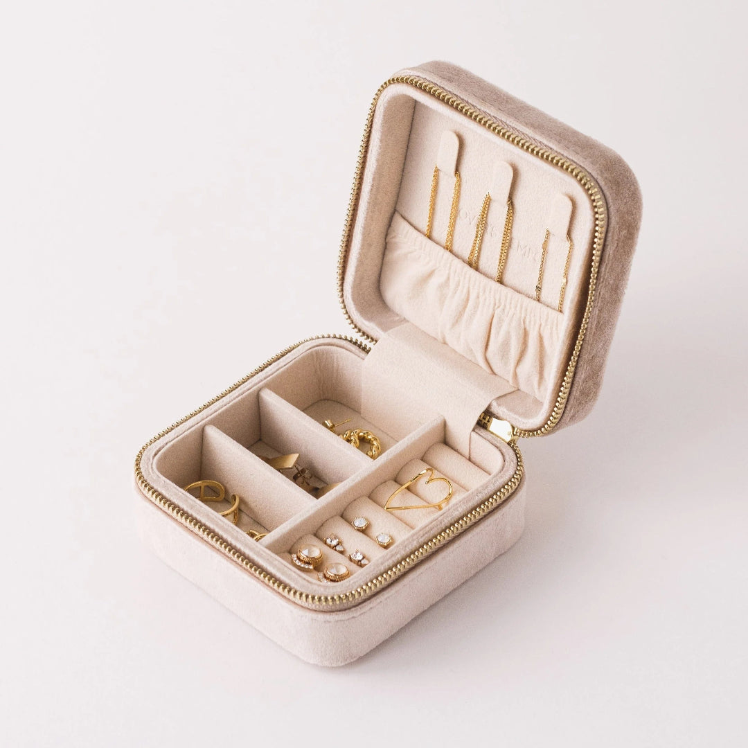 Beige jewelry box with gold earrings on a white background