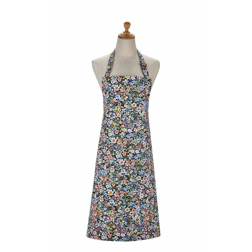 A floral apron with a halter neck design, featuring a multicolored flower pattern on a white background, displayed on a mannequin.