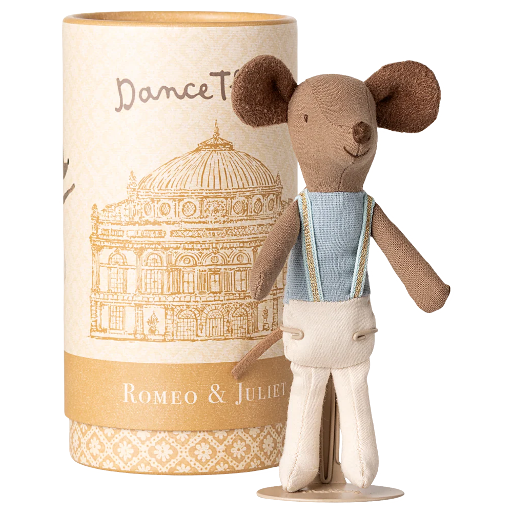 Stuffed toy mouse in a costume standing next to a cylindrical packaging with architectural design and text.