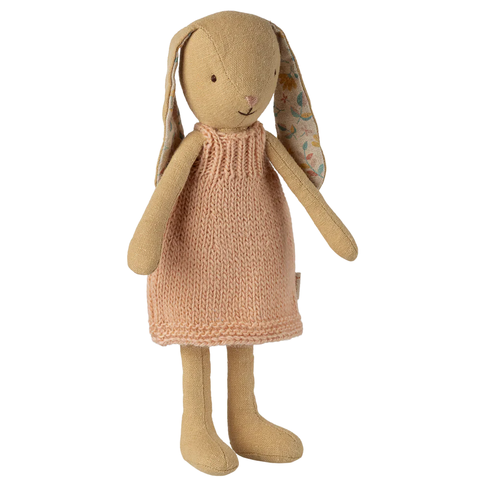 Stuffed bunny toy wearing a knitted dress on a white background