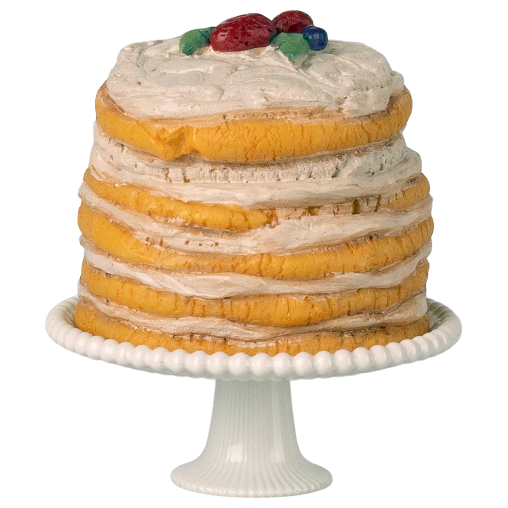 Layered cake with white frosting and fruit on top, placed on a white cake stand.