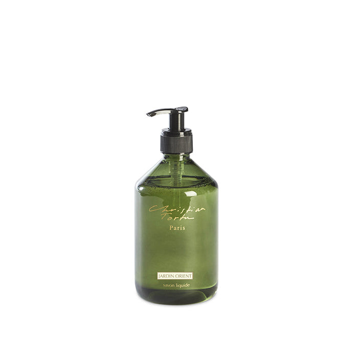 A clear pump bottle with green liquid soap, labeled 'Christian Tortu Jardin Orient'.