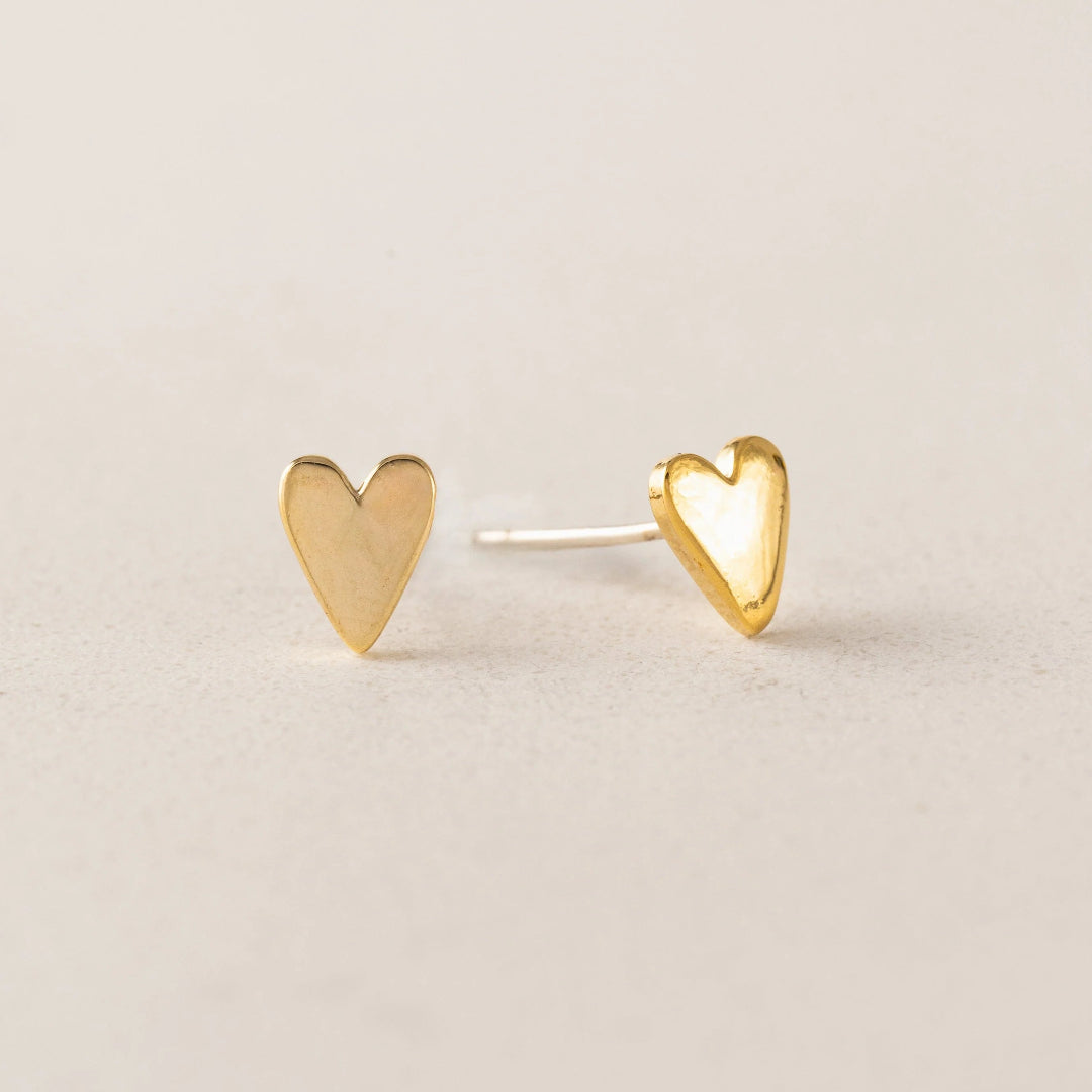 Heart-shaped gold earrings on a beige background