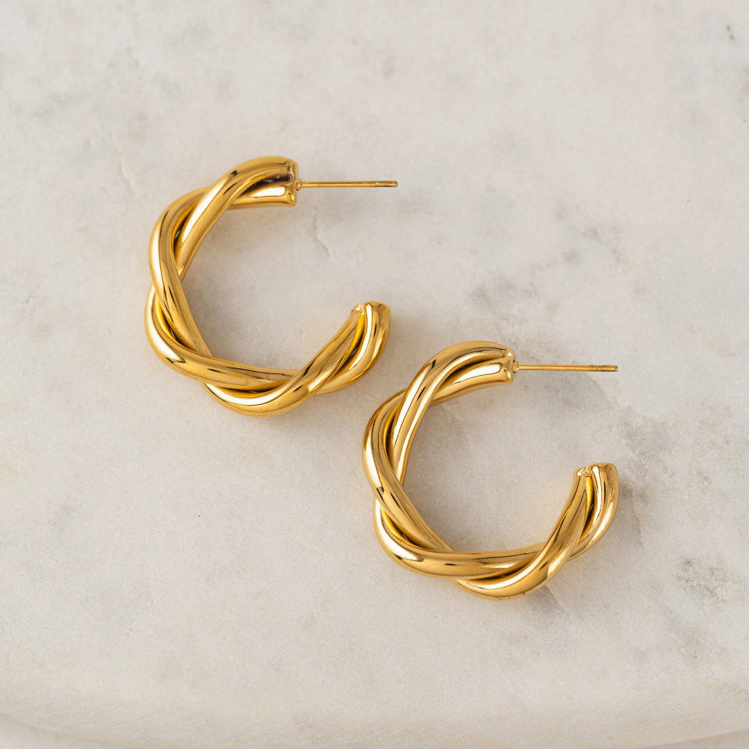 Gold hoop earrings on a marble surface