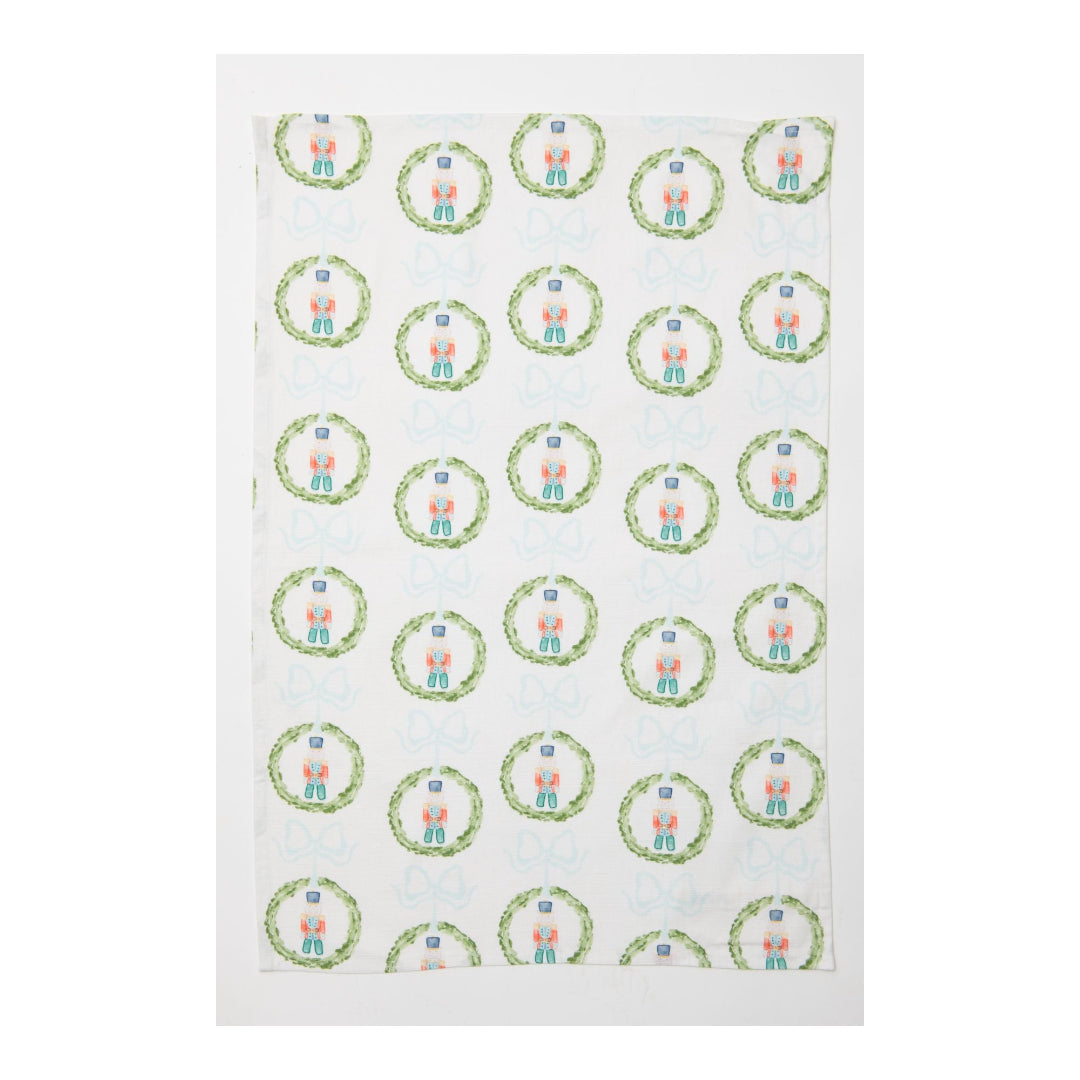 Tea towel with green wreaths & nutcrackers on a white background