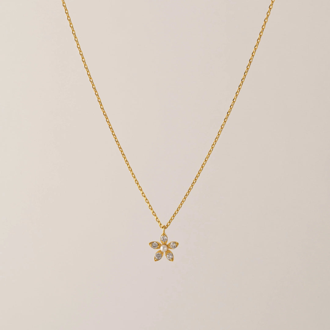 Gold necklace with a delicate pendant on a beige background