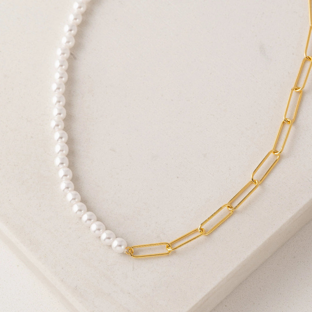 Pearl necklace with a gold chain on a light background