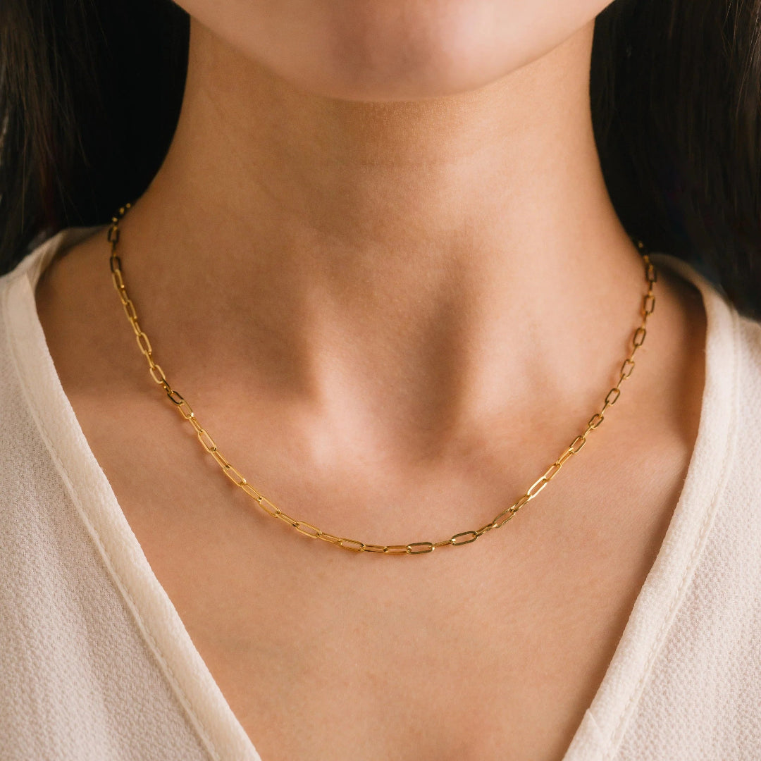 Gold chain necklace on a person wearing a beige top