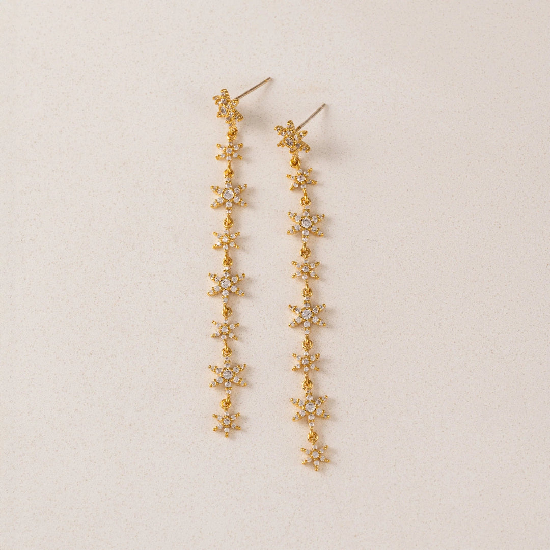 Gold floral earrings on a beige background