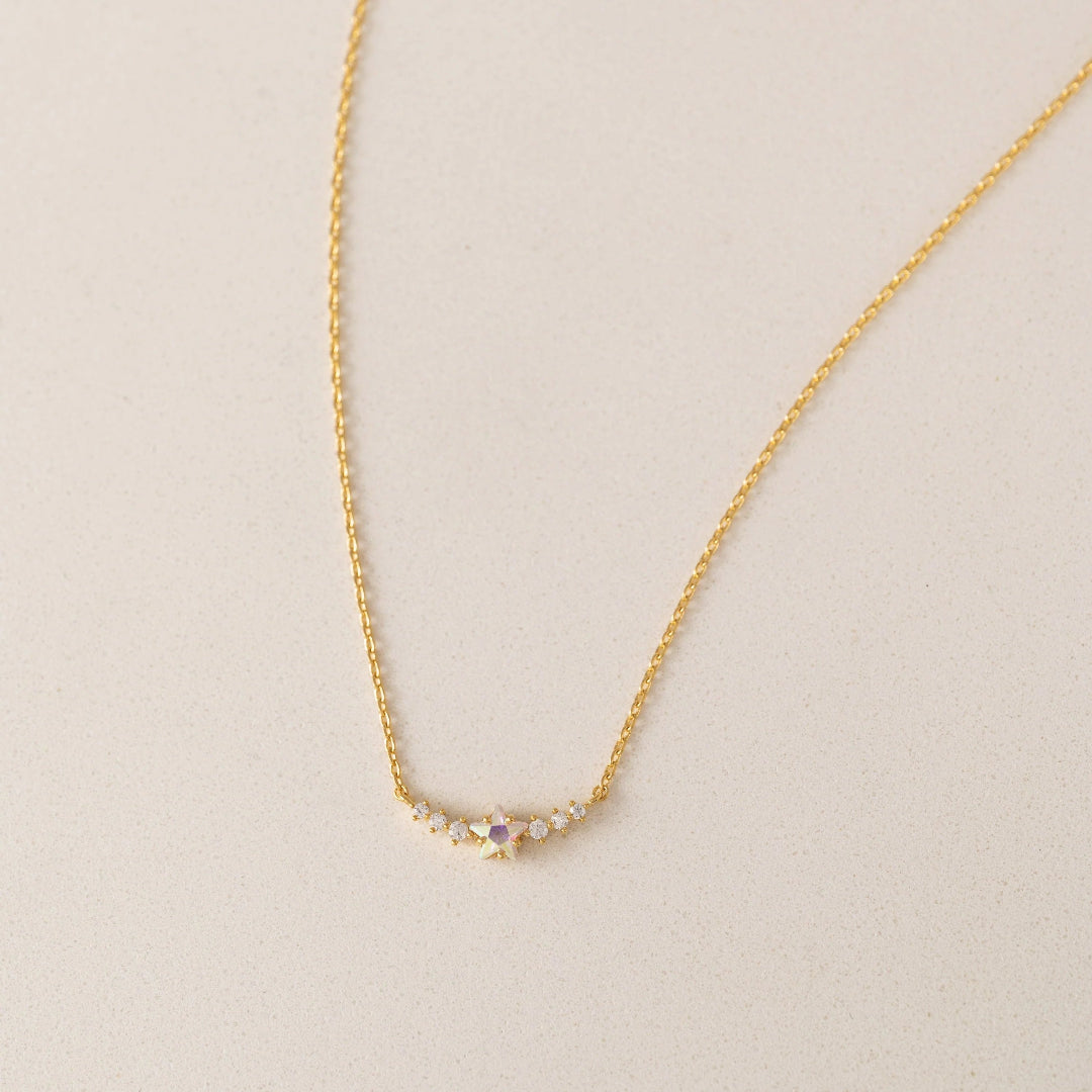 Gold necklace with small gemstones on a beige background