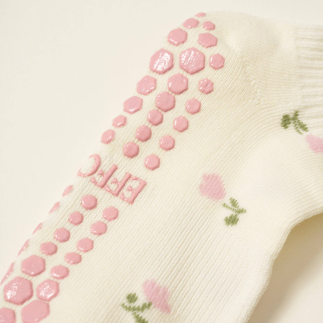Cream sock with pink non-slip dots and floral design on a light background