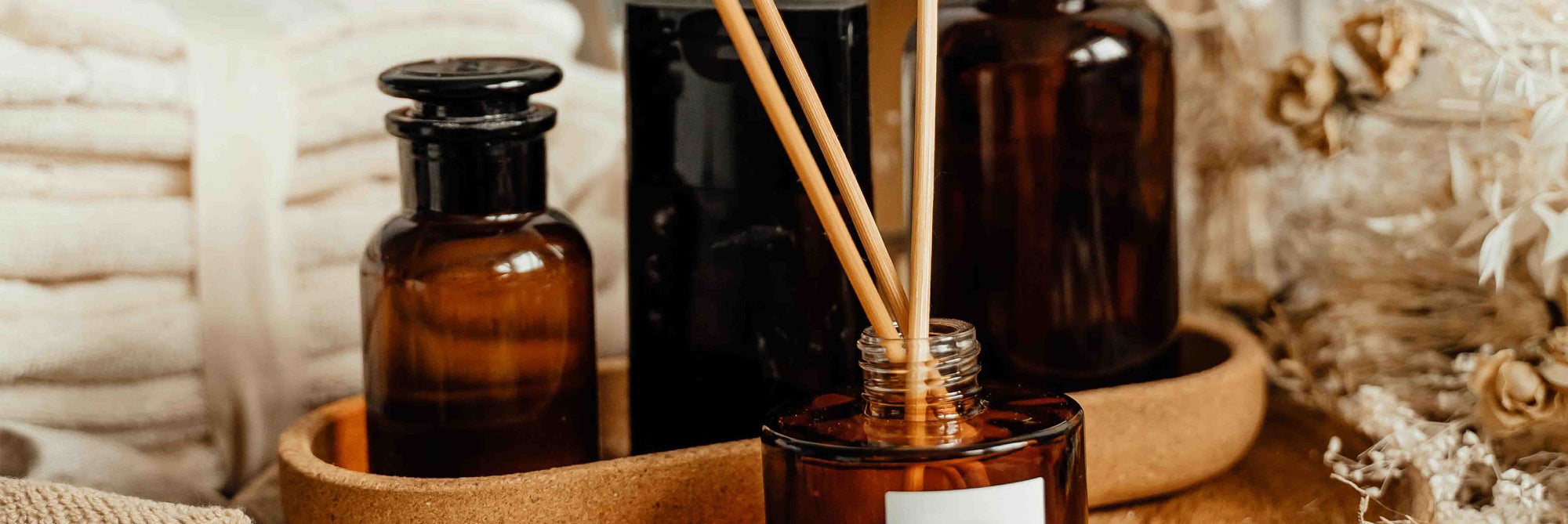 Aromatherapy diffuser with essential oil bottles and reeds on a textured surface.