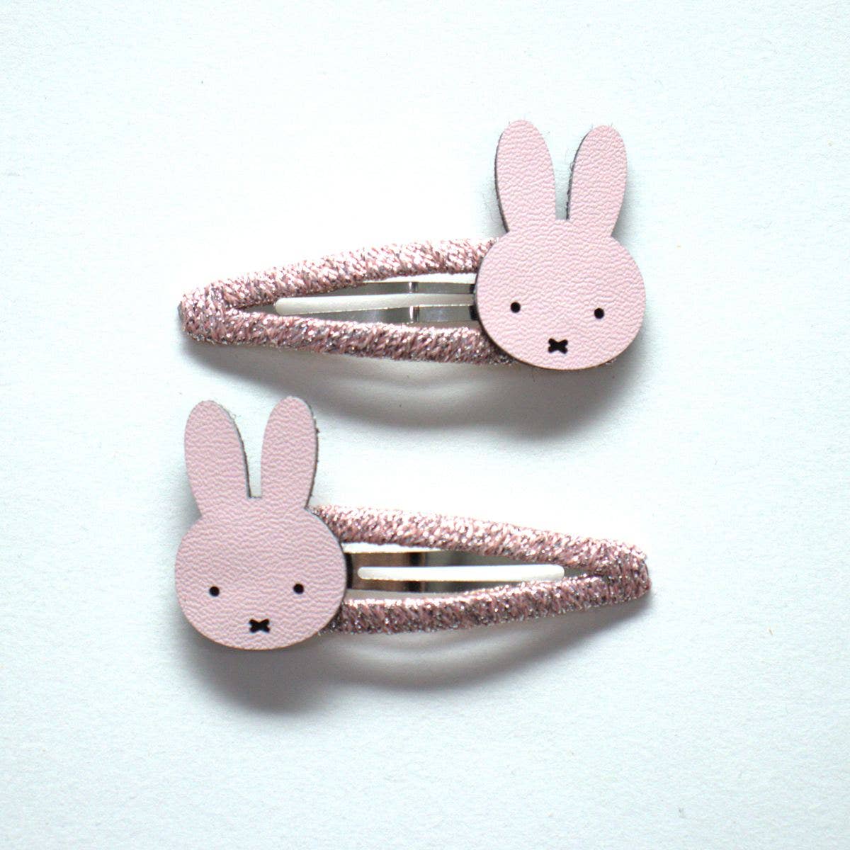 Two pink rabbit-shaped hair clips on a white background