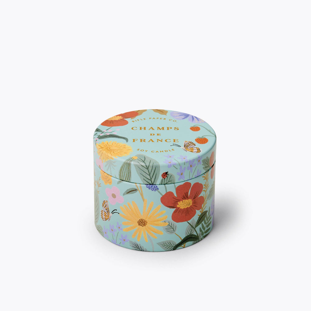 A 3 oz tin candle with a floral design lid, labeled 'Champs de France' by Rifle Paper Co.