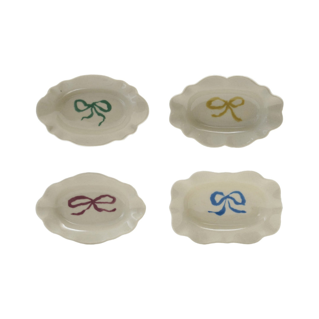 Four small ceramic dishes with colorful bow designs on a white background