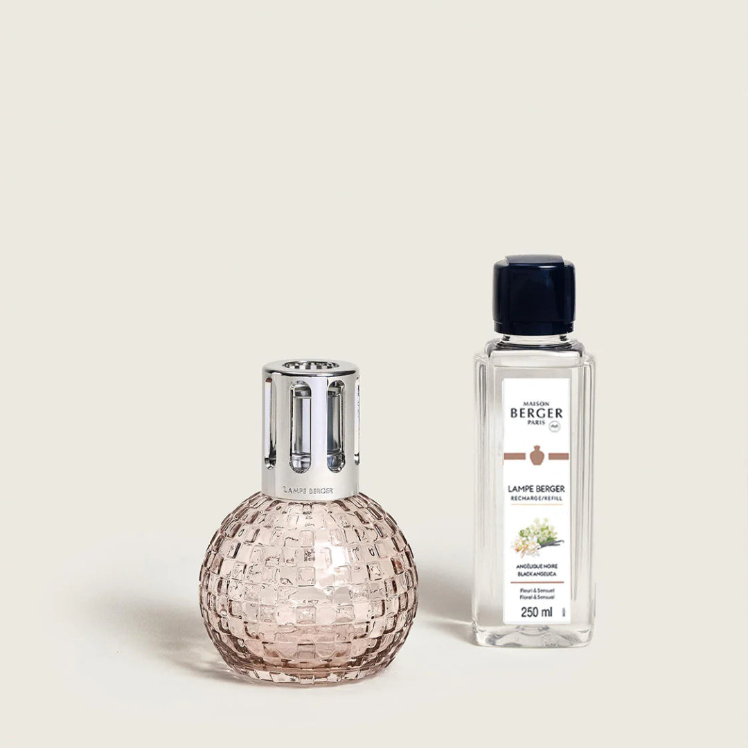 Pink glass diffuser and clear bottle with label on a light beige background